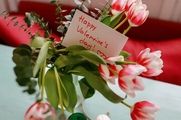 Bouquet of tulips on the table with a card and hearts. Valentines flat lay concept. Top view.
