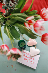 Bouquet of tulips on the table with a card and hearts. Valentines flat lay concept. Top view.