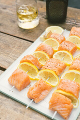 Grilled salmon and lemon skewers on a smokey bbq during a summer day with a whisky drink