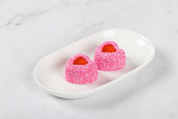 Festive Strawberry cream mousse desserts with jelly filling, in the shape of a heart, sprinkled with pink coconut chips. On a plate. White background. Valentine's day