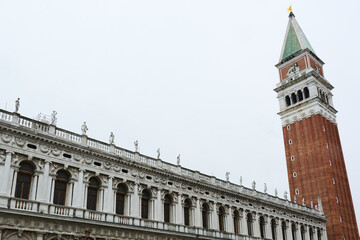 Fototapeta na wymiar Details of the building of the Marciana National Library with the Campanile di San Marco (bell tower) on the right on cloudy day.