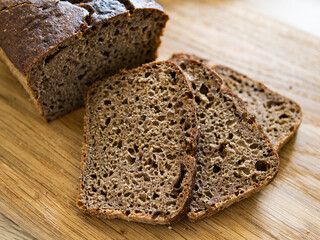Top view of sliced wholegrain rye bread on wooden background closeup.