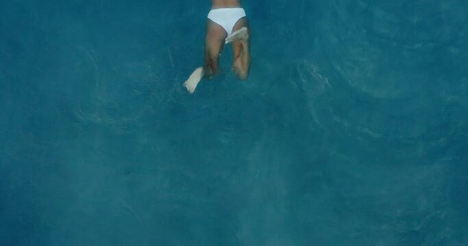 Aerial view of beautiful woman swimming in the the pool at luxury resort spa at sunrise