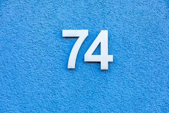 house number 74 wirth blue wall background