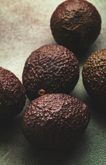 Ripe brown avocado on rusty green kitchen table background, top view