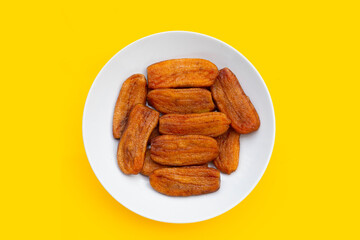Sun dried bananas on yellow background.