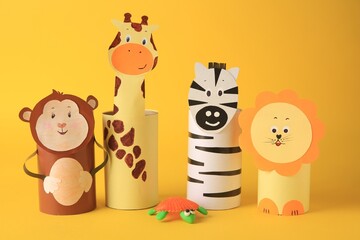 Toy monkey, giraffe, lion and zebra made from toilet paper hubs on yellow background. Children's handmade ideas