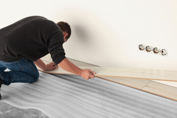 Professional worker installing new laminate flooring. Space for text