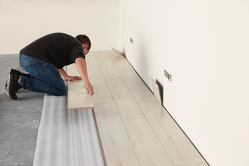 Professional worker installing new laminate flooring. Space for text