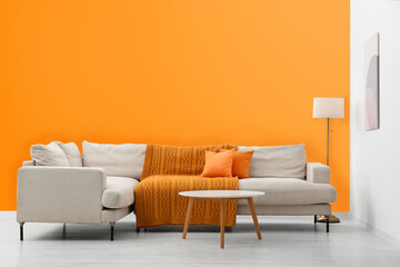 Stylish sofa and coffee table in room with orange walls. Interior design