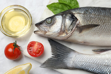 Sea bass fish and ingredients on white marble table, flat lay