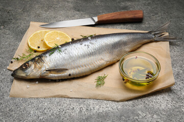 Delicious salted herring, olive oil, lemon and dill on grey table