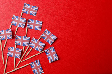 Small paper flags of United Kingdom on red textured background, flat lay. Space for text