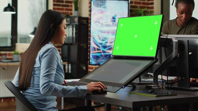 Creative agency employee looking at greenscreen and 3d developing software on touchscreen monitor. Working with isolated chroma key display and using game infographics, copyspace. Tripod shot.