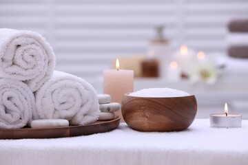Obraz na płótnie Canvas Spa composition with rolled towels and burning candles on massage table in wellness center