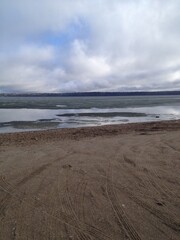lake with some ice with the landscape view across the lake with a small beach with sand (no trees)