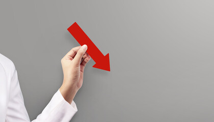 Woman holding red graph chart arrow that is pointing down at grey background. Concept of Global Recession.
