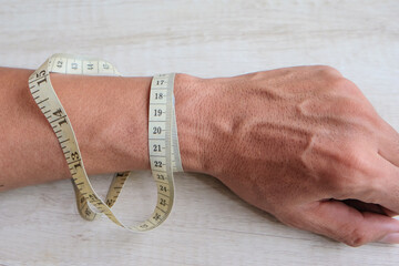 Male hand measuring wrist with measuring tape