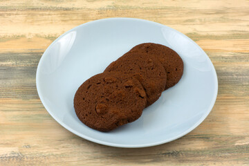 Three chocolate cookies with chocolate chips on blue snack plate 