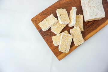 Raw Tempeh or Tempe. Tempeh Slices on Wooden Background and white isolated. Copy Space for Text

