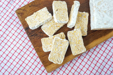 Raw Tempeh or Tempe. Tempeh Slices on Wooden Background and white isolated. Copy Space for Text
