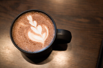 Delicious hot mocha with froth art on top put on wooden table. Close up