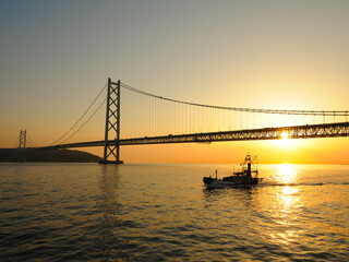 夕日と吊り橋と漁船のシルエット