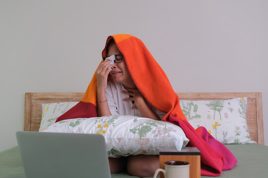 Facial expression of a girl looking sad, watching drama alone in her bedroom, using laptop