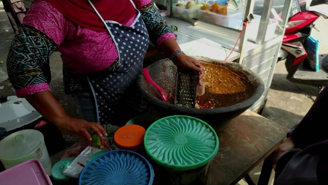 indonesian elderly woman with hijab  and mask selling traditional spicy salad with peanut sauce with couple of people in line