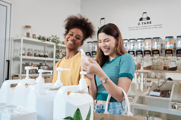 Two female customers are happy and enjoy shopping with natural organic products with recycled bottles at zero-waste and refill store, environment-friendly groceries, and sustainable lifestyles retail.