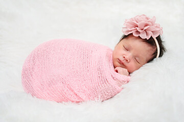 happy newborn baby girl sleeping in cloth wrap blanket on bed.