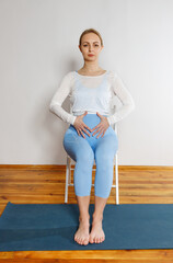 A young girl sits on a chair and holds her stomach. Pregnant woman at an early stage. Concept against abortion.