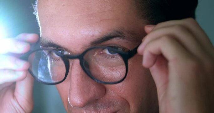 Pensive business man put on glasses and work at computer, monitor screen reflection on glasses. Reflections in computer glasses of business man browsing internet pages and working at night, close up