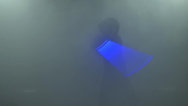 Young man in Jedi cosplay costume with lightsaber battle on black background in smoke and rain, 4k slow motion video filmed on 8k camera nikon z9