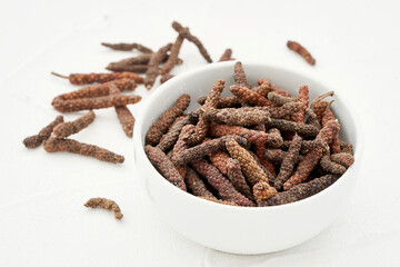 long pepper or piper longum in plate on white table background. heap of long pepper or piper longum. long pepper, piper longum                                                        