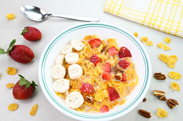 Cornflakes cereal served in a bowl with strawberry, banana and nuts.