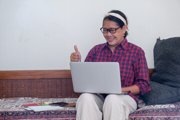 woman sitting on the sofa while working on computer on her lap