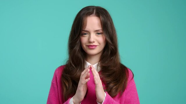 Close-up view of tricky girl looking at camera while making a gesture with her hands. Portrait of a young, caucasian woman feeling cheerful and smiling. High quality 4k footage