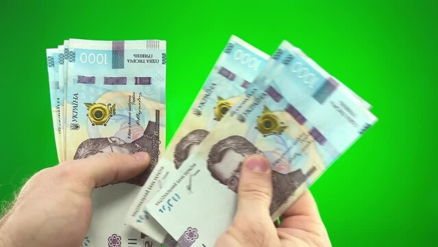 Background 1000 hryvnias. Money texture. Many Ukrainian hryvnias. Ukrainian banknote with Volodymyr Vernadsky On a green background, chroma key male hands count hryvnia large bills