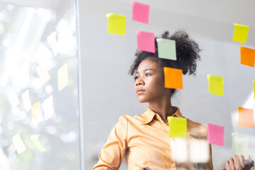 Young Serious african american Creative team use post it notes to share idea sticky note on glass...