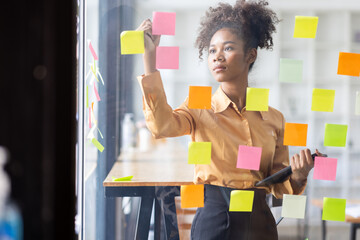 Young Serious african american Creative team use post it notes to share idea sticky note on glass...