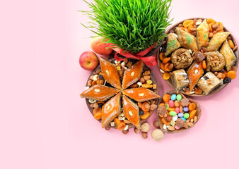 Nowruz festive table. green wheat grass with red ribbon, arabic dessert baklava, sweets, nuts, dry...