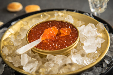Orange Keta Lachs Kaviar in Dose auf Eis in Glas Schale mit Perlmutt Löffel, Sekt Champagner und...