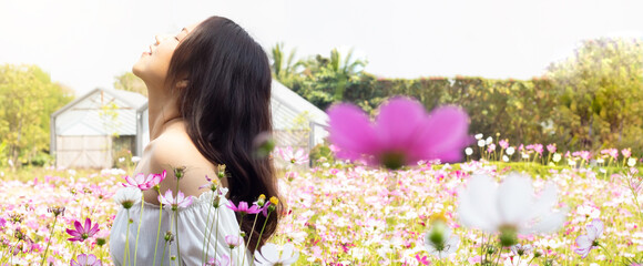 Portrait calm beautiful smiling young asian woman with ponytail breathing fresh air outdoor, relaxing with eyes closed, feeling alive, breathing, dreaming. flower garden park nature background.