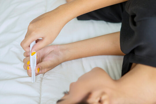 Woman hands holding ovulation test in bed