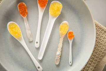 Kaviar von orange Keta Lachs und gelb Saibling mit Auswahl von Löffel aus Perlmutt, Plastik,...