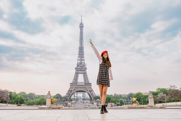 Beautiful young woman visiting paris and the eiffel tower. Parisian girl with red hat and fashionable clothes having fun in the city center and landmarks area - obrazy, fototapety, plakaty
