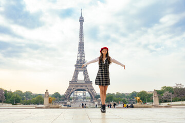 Fototapeta na wymiar Beautiful young woman visiting paris and the eiffel tower. Parisian girl with red hat and fashionable clothes having fun in the city center and landmarks area