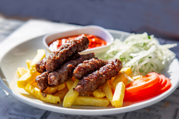 grilled cutlets with fried potatoes tomatoes and onion in the white plate 