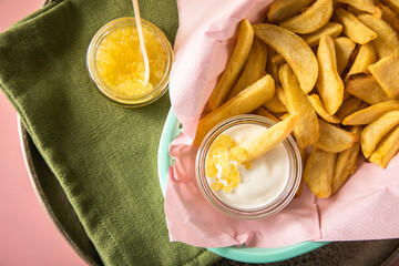 Gelber Saiblings Kaviar mit Perlmutt Löffel zu Pommes, Saure Sahne und Champagner Sekt in Korb rosa auf Serviette grün und Hintergrund Pastell Pink